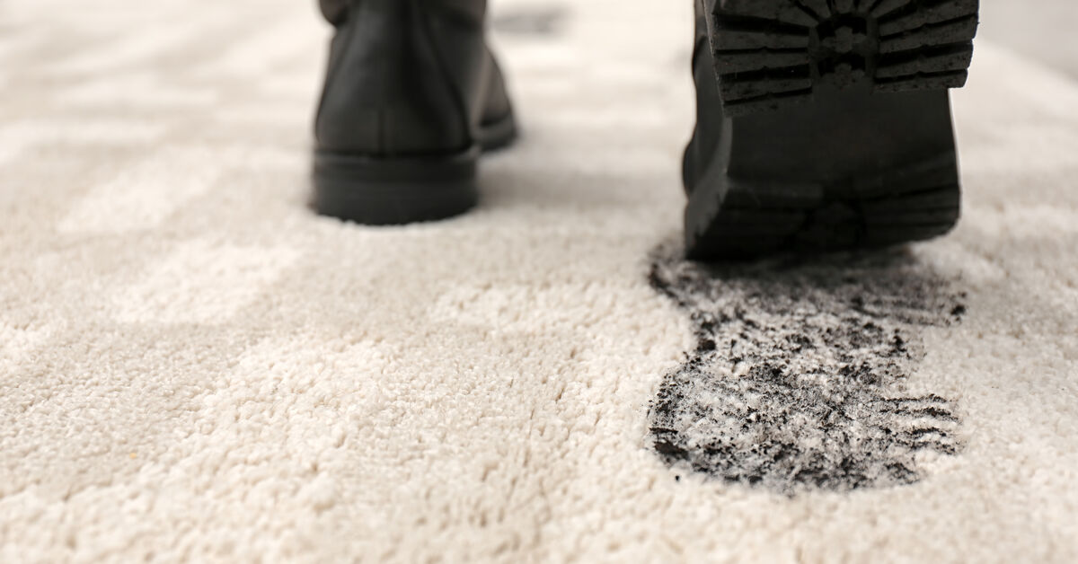 Muddy shoes next to dirty carpet